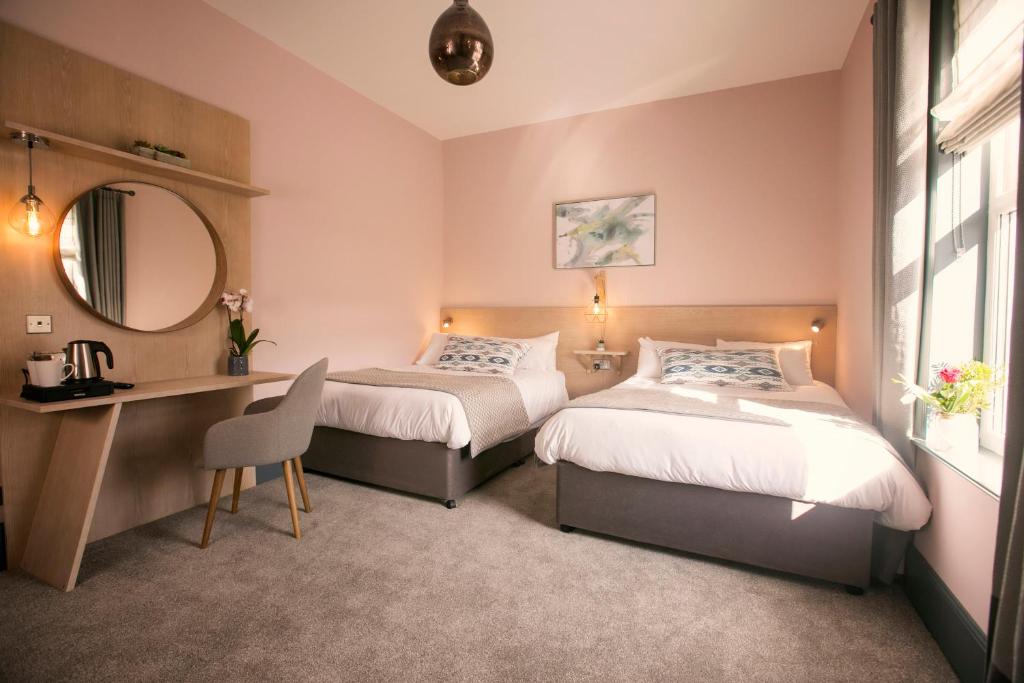 een slaapkamer met 2 bedden, een bureau en een spiegel bij The Fullerton Arms in Ballintoy