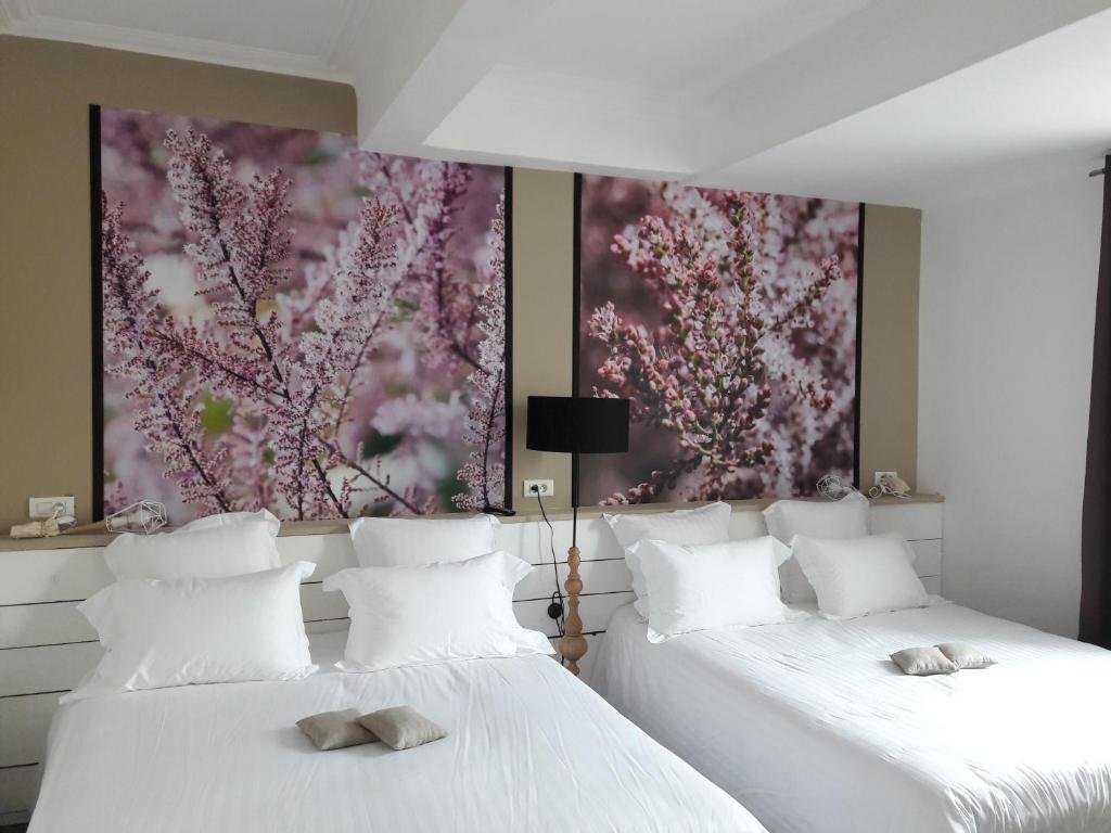 2 Betten in einem Zimmer mit Wandgemälde in der Unterkunft Hôtel-Restaurant "Chez Carrière" in Aigues-Mortes