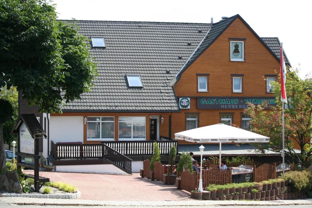 un gran edificio con una sombrilla delante de él en Gasthaus-Pension Herberger, en Kurort Oberwiesenthal