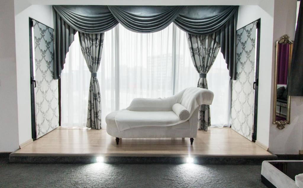 a white chair sitting in front of a large window at Hotel Jolie Apartments in Galaţi