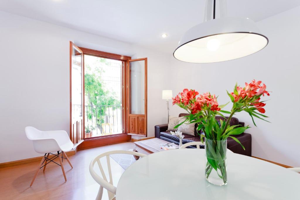 a living room with a table with flowers in a vase at San Miguel Aparment by Flatsweethome in Madrid