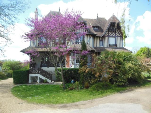 une maison avec un violet arbre en face dans l'établissement Maison d'hôtes Il était une fois, à Pont-l'Évêque