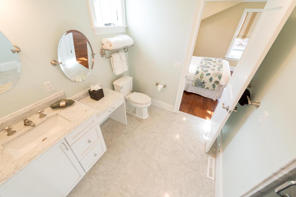 een badkamer met een wastafel, een toilet en een spiegel bij The Newport Lofts - 546 Thames Street in Newport
