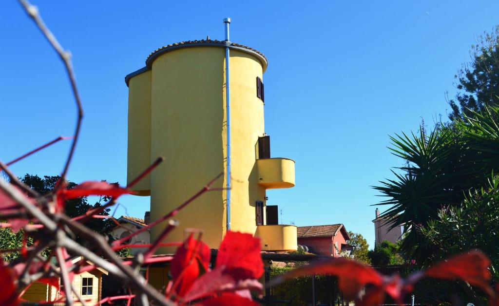 un château d'eau avec des fleurs rouges devant lui dans l'établissement Il Silos, à Maccarese