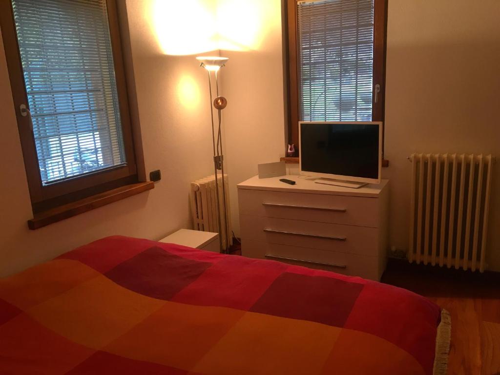 Dormitorio con cama y tocador con TV en La maison de vali en Aosta