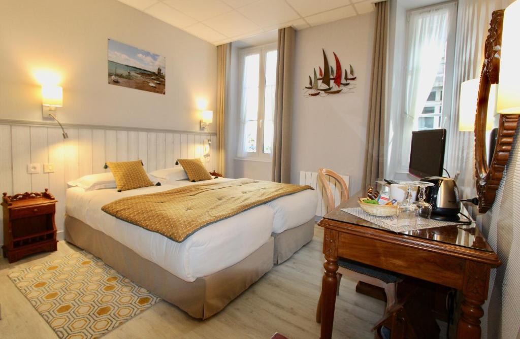 um quarto com uma cama e uma secretária com uma televisão em Hotel des Abers em Saint Malo