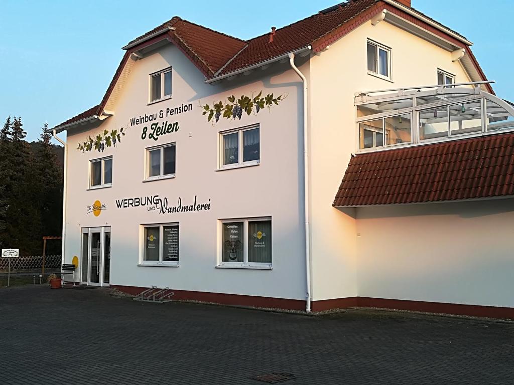 un bâtiment blanc avec des écritures sur son côté dans l'établissement Weinbau & Pension "8Zeilen", à Golk