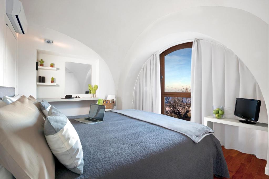 biała sypialnia z łóżkiem i oknem w obiekcie Montebosco Luxury Country House w mieście Piano di Sorrento