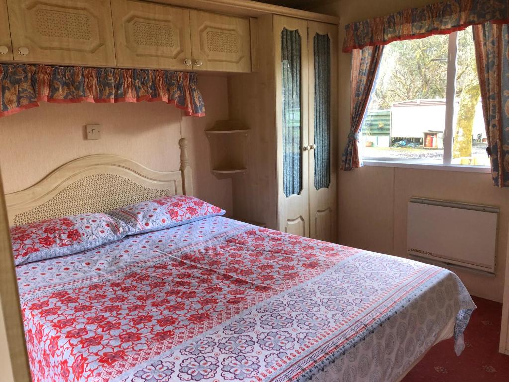 a bedroom with a bed with a red and white quilt at 35 Glenfinart Park in Dunoon