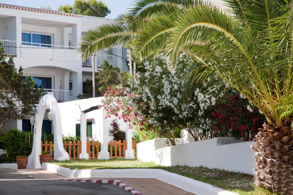 a white building with a palm tree in front of it at Camelina Suites in San Antonio Bay