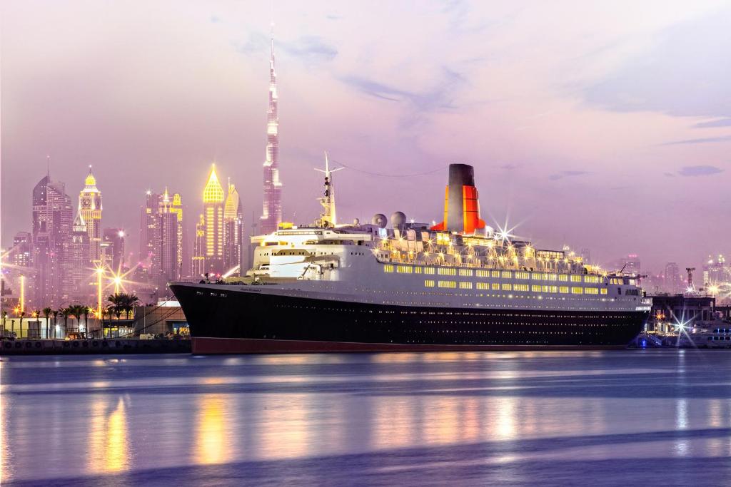 un crucero en el agua frente a una ciudad en Queen Elizabeth 2 Hotel, en Dubái