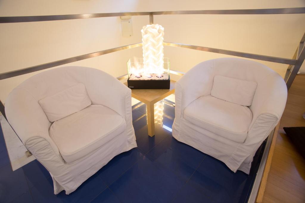 two white chairs sitting next to a table with a lamp at Baia Blu RTA Residence in Lerici
