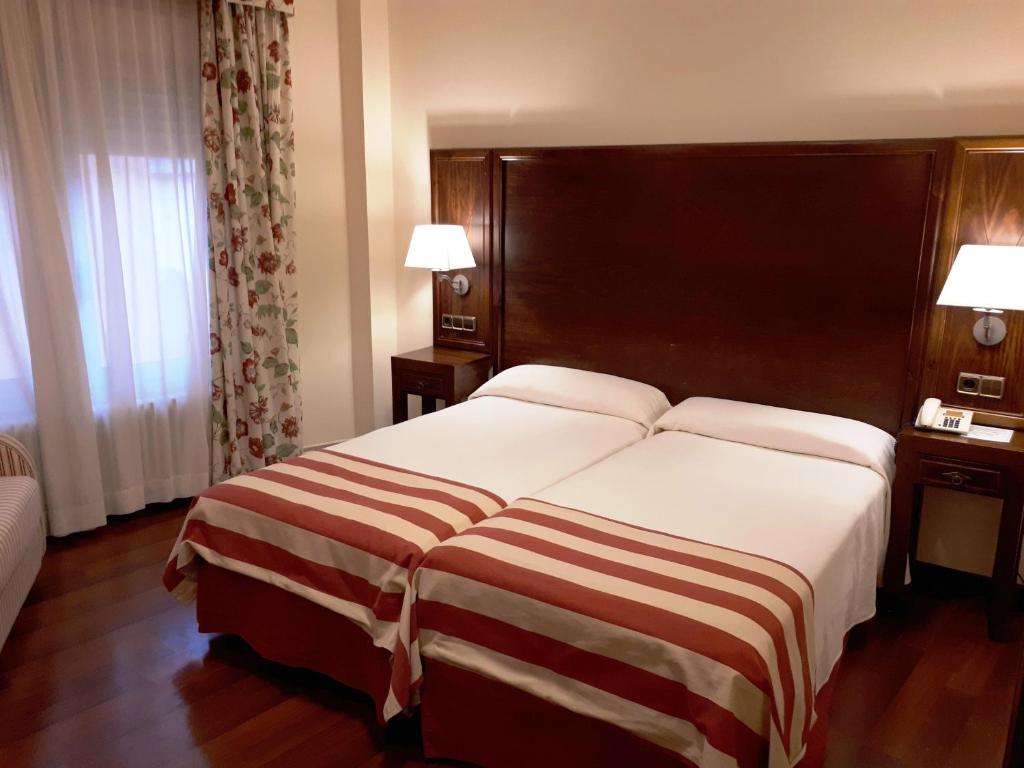 a hotel room with a large bed and two lamps at Hotel Urogallo in Vielha