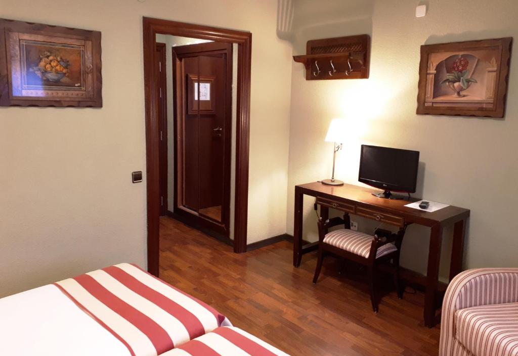 a hotel room with a desk with a television and a bed at Hotel Urogallo in Vielha