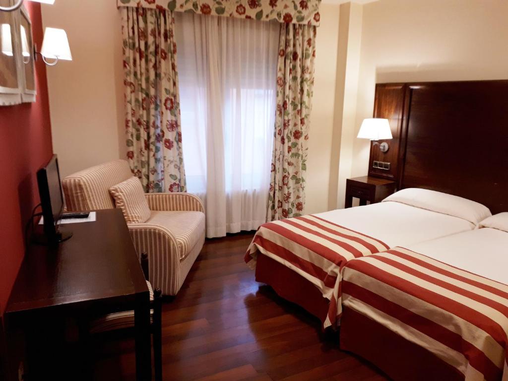 a hotel room with a bed and a desk and chair at Hotel Urogallo in Vielha