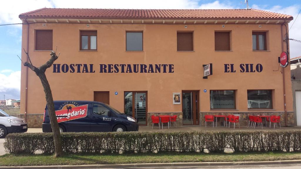 a building with a hotel restaurant with red chairs at Hostal Restaurante El Silo in Santa María del Páramo