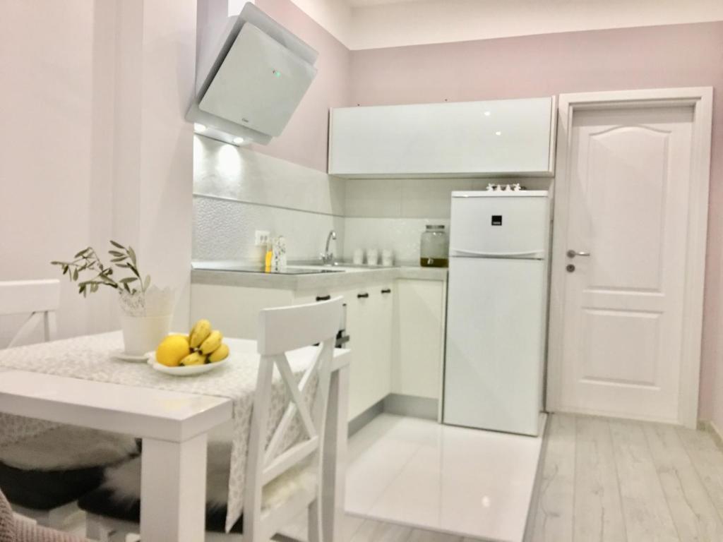 eine weiße Küche mit einem Tisch und einem weißen Kühlschrank in der Unterkunft Apartments Talija Podgora in Podgora