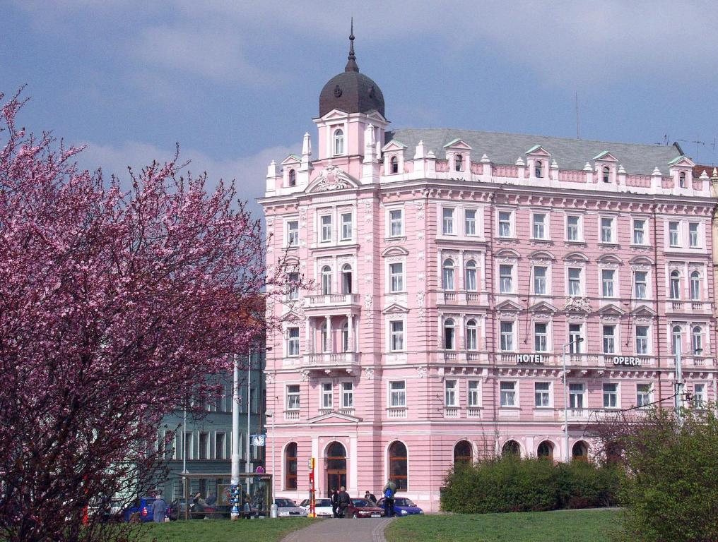 un grand bâtiment rose avec un dôme en haut dans l'établissement Hotel Opera, à Prague