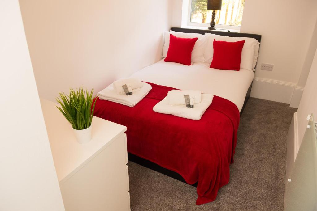 バーミンガムにあるMoseley Mews Village Suitesのベッドルーム1室(大型ベッド1台、赤い枕付)