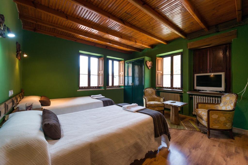 Habitación verde con 2 camas y TV. en Hostal Peña Santa, en Soto