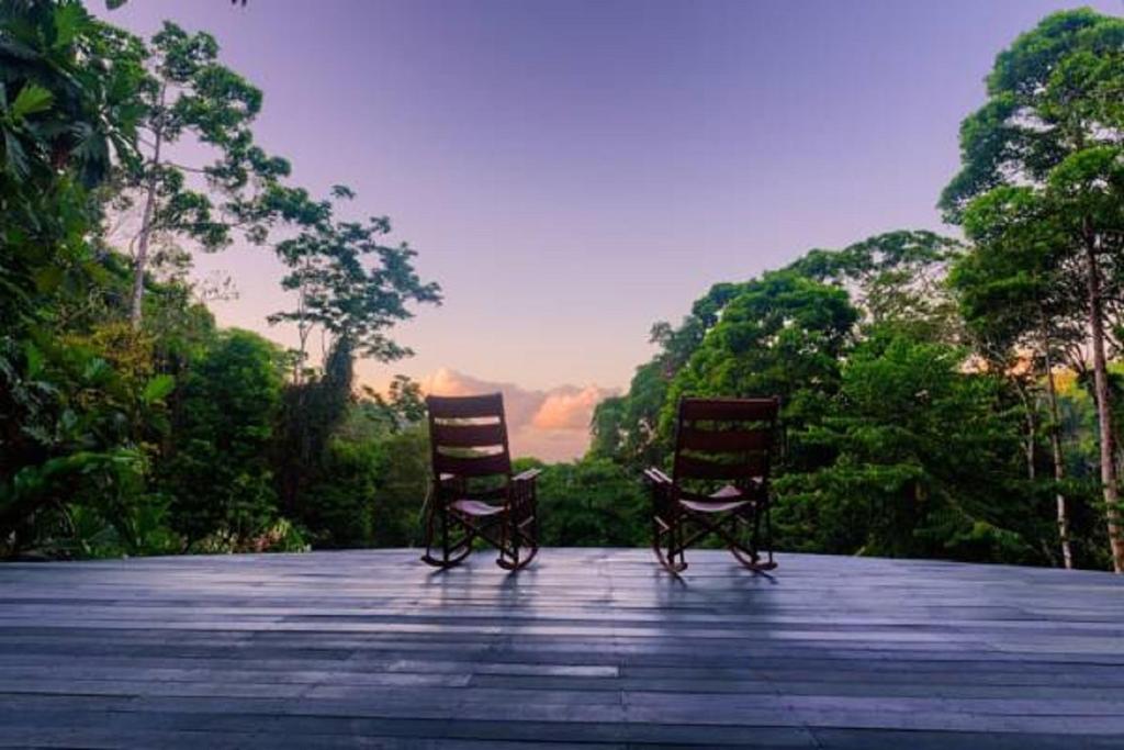 2 chaises assises au-dessus d'une terrasse en bois dans l'établissement Luna Lodge, à Carate