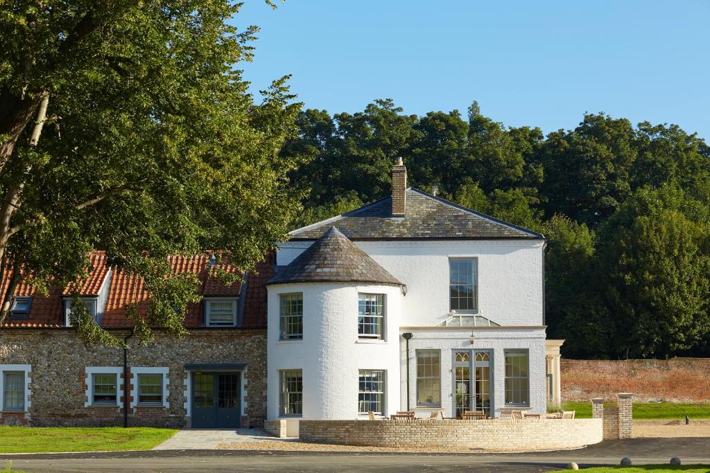 a white house with a brick wall and trees at The White House in Burnham Market