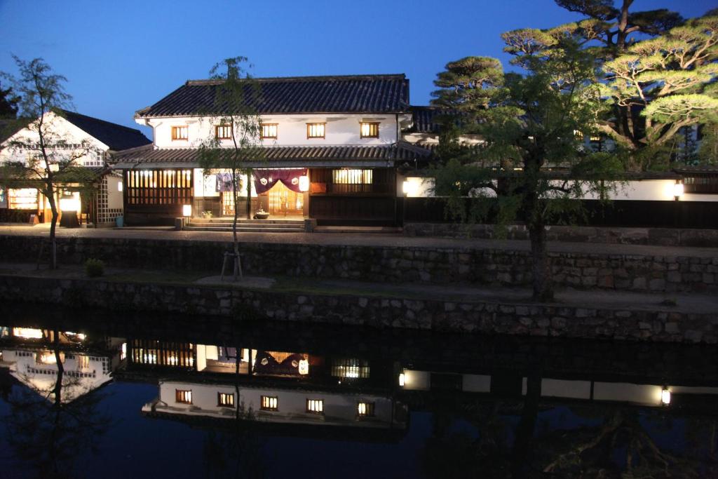 une maison éclairée sur l'eau la nuit dans l'établissement Ryori Ryokan Tsurugata, à Kurashiki