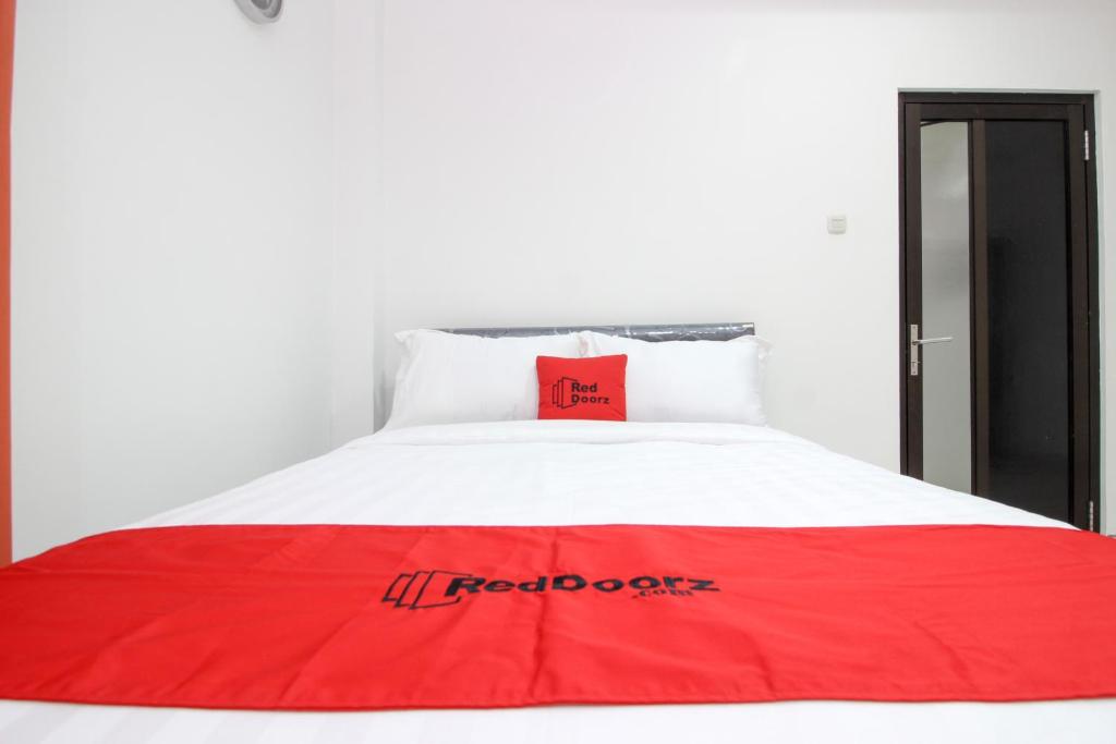 a red blanket on top of a white bed at RedDoorz Plus @ Affandi Gejayan in Yogyakarta