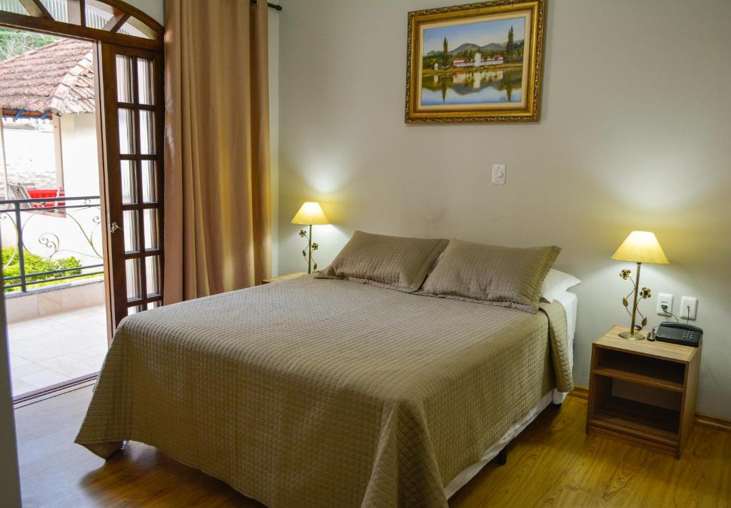 1 dormitorio con 1 cama y puerta a un balcón en Hotel Real São Lourenço en São Lourenço