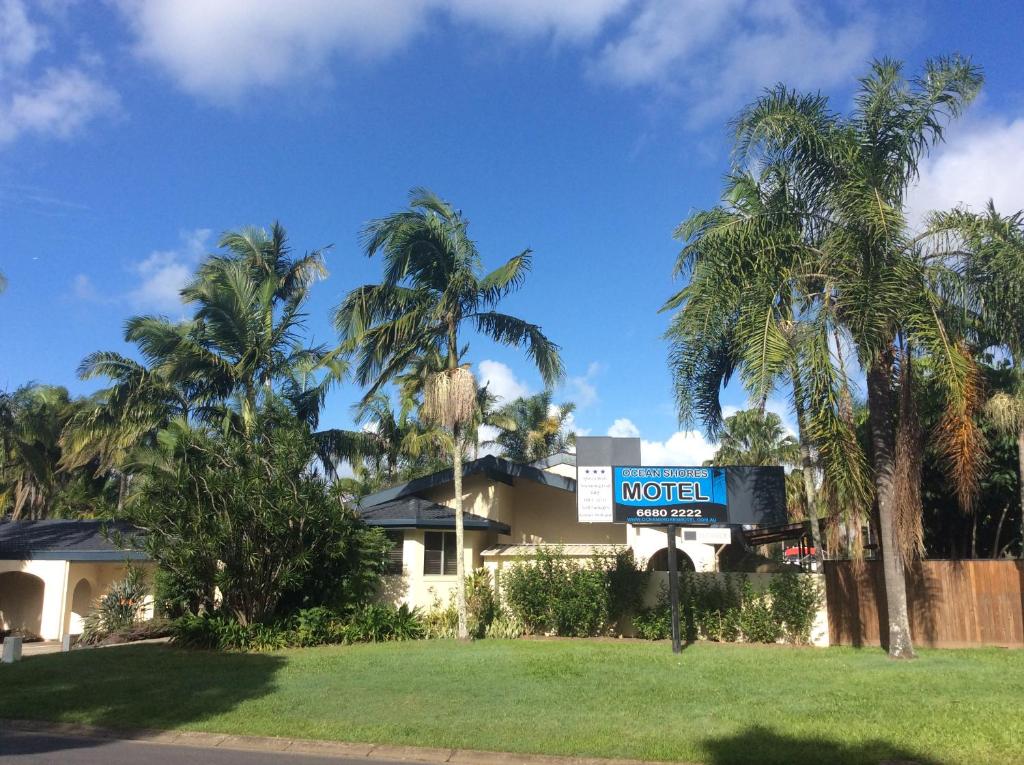 a motel sign in front of a building with palm trees at Ocean Shores Motel in Ocean Shores