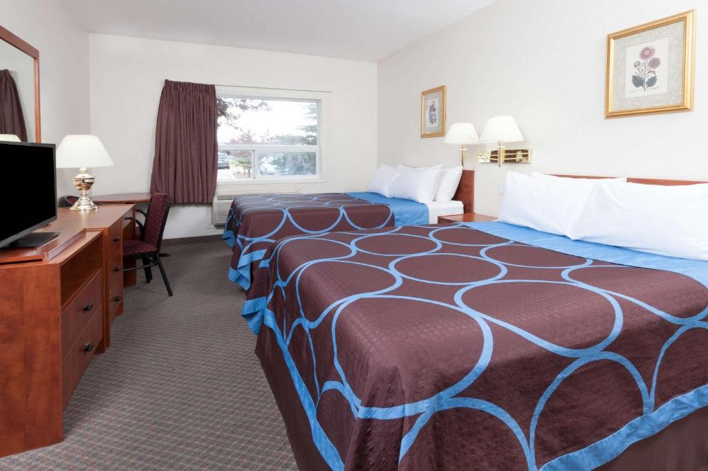 a hotel room with two beds and a desk and a television at Super 8 by Wyndham Edmonton/West in Edmonton