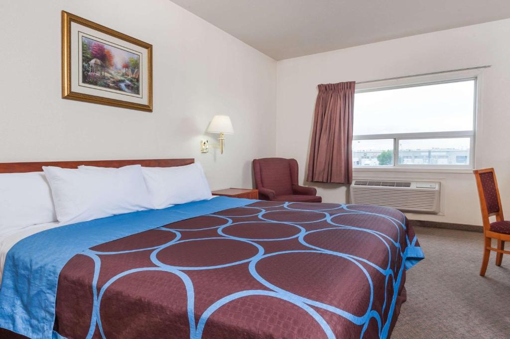 a hotel room with a bed and a chair and a window at Super 8 by Wyndham Edmonton/West in Edmonton