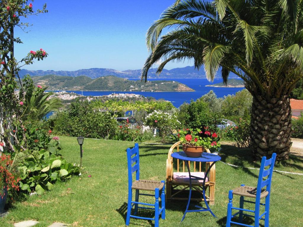 a table and chairs in the grass with a palm tree at Skiathos Studios Panorama in Skiathos Town