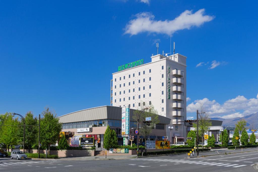 un edificio blanco con una señal verde encima en Sakudaira Plaza 21, en Saku