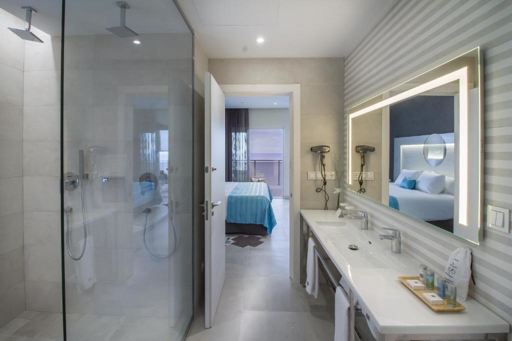 a bathroom with two sinks and a shower and a bed at ESTIMAR Calpe Suitopia in Calpe