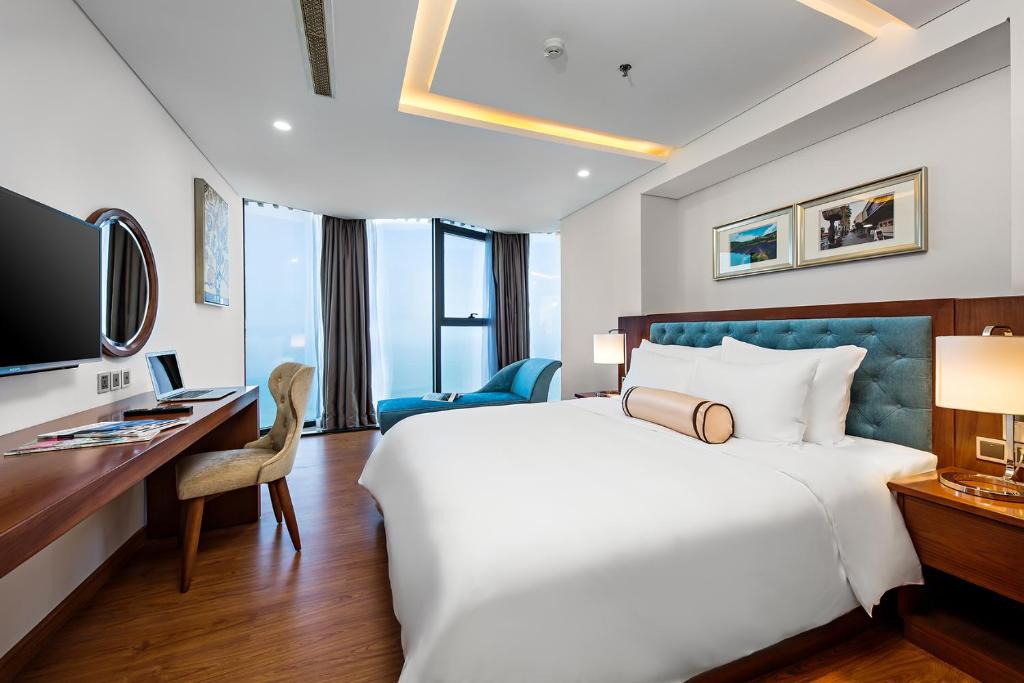 a hotel room with a large bed and a desk at Paris Deli Danang Beach Hotel in Danang