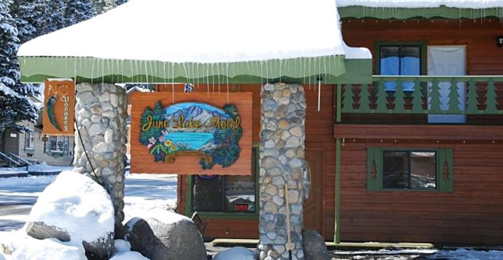 een gebouw met een bord in de sneeuw bij June Lake Motel in June Lake