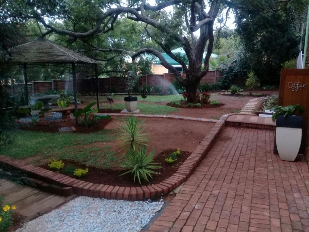 a garden with a brick walkway and a tree at Shalamanzi Lodge in Hartbeespoort