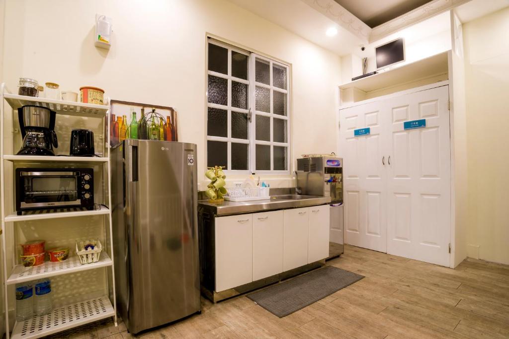 a kitchen with a stainless steel refrigerator and white cabinets at Hualien Bird's House Hostel in Hualien City