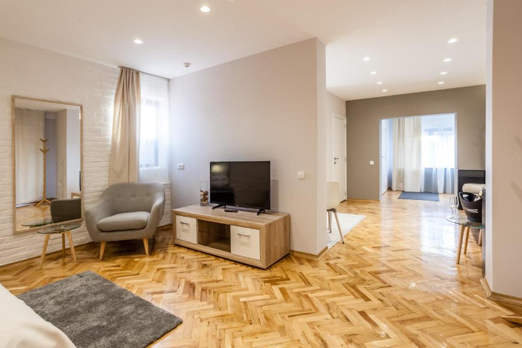 a living room with a flat screen tv and a chair at Apartmani studio in Zrenjanin