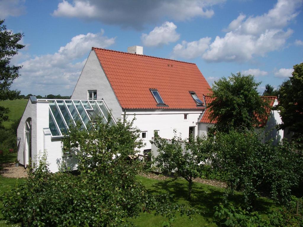 uma casa branca com um telhado vermelho com uma estufa em Natursti Silkeborg Bed & Breakfast em Them