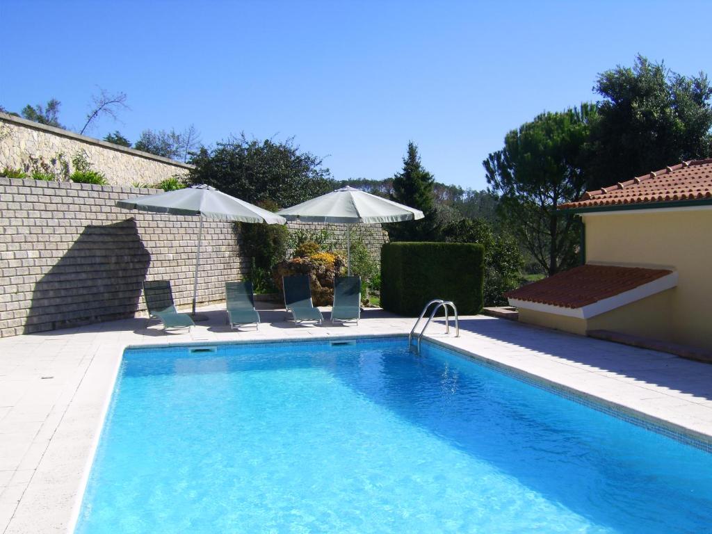 a large swimming pool with chairs and umbrellas at Casa Bela Vista in Bem da Fé