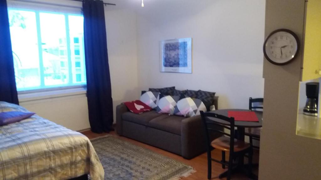 a room with a couch and a table and a clock at Cosy studio apartment in Vaasa