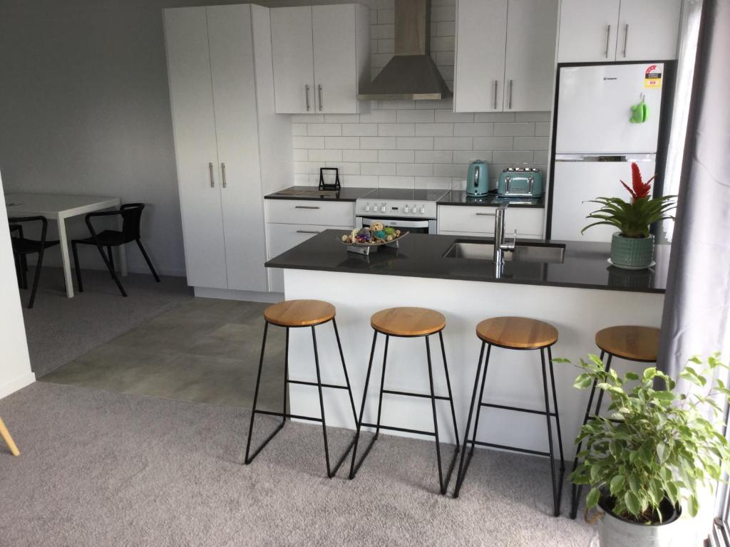 a kitchen with three bar stools and a counter at 2BD Family or Couple Guesthouse Upstairs near Turf club, HOTA in Bundall in Gold Coast
