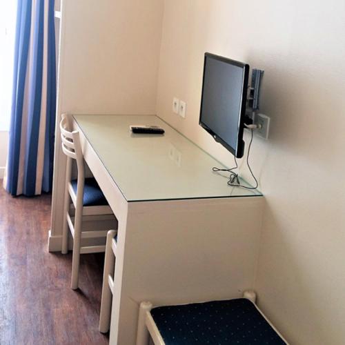 a desk with a computer and a monitor on it at Hotel Le Havre Bleu in Beaulieu-sur-Mer
