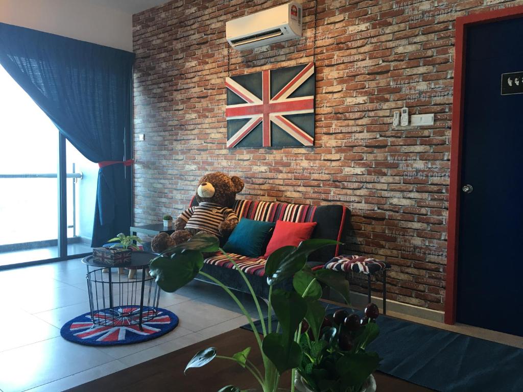 a teddy bear sitting on a couch against a brick wall at Eye of London @ Central Malacca in Melaka