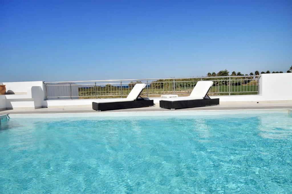 a swimming pool with two lounge chairs next to it at Hestia in Kos Town