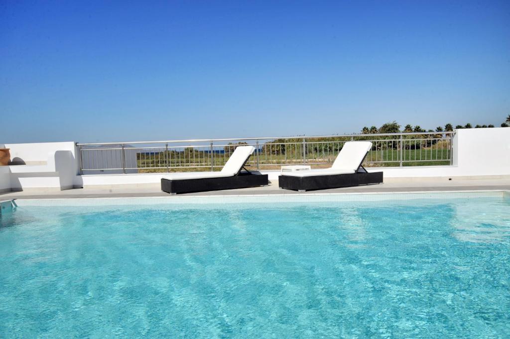 a swimming pool with two lounge chairs next to it at Hestia in Kos
