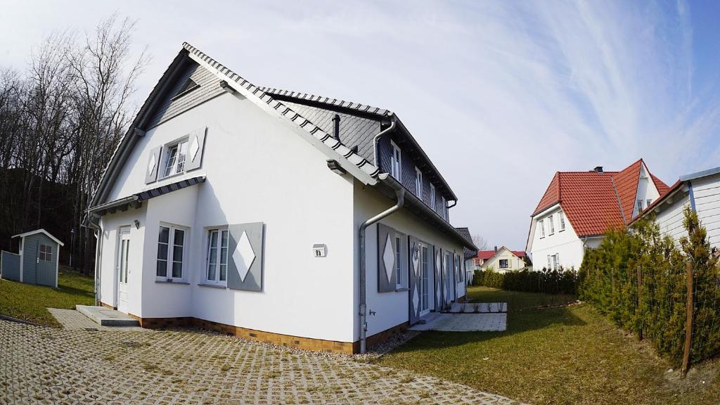 a white house with a black roof at Strandvilla Thiessow in Thiessow