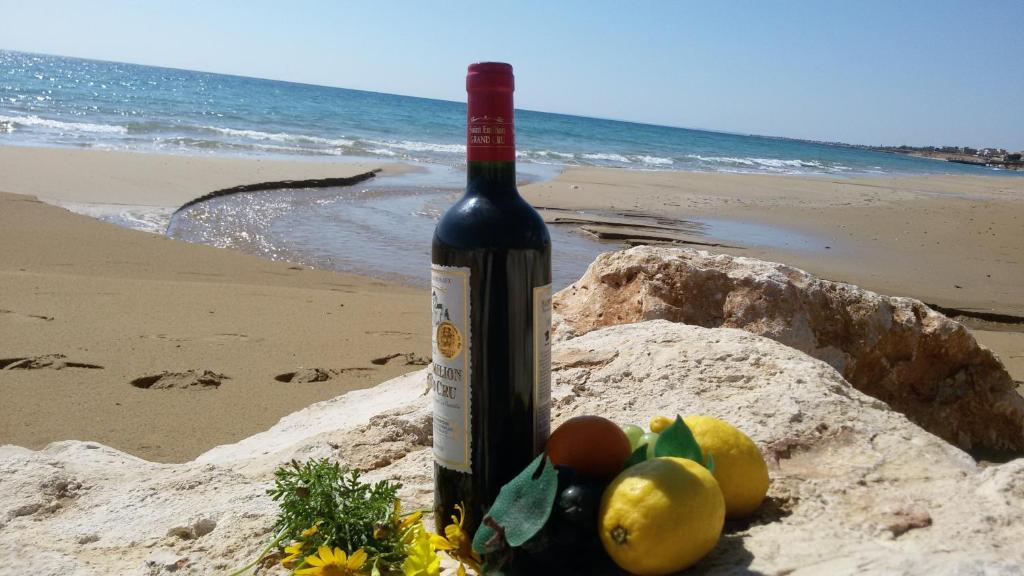 a bottle of wine sitting on the beach at Krizia Mare in Avola